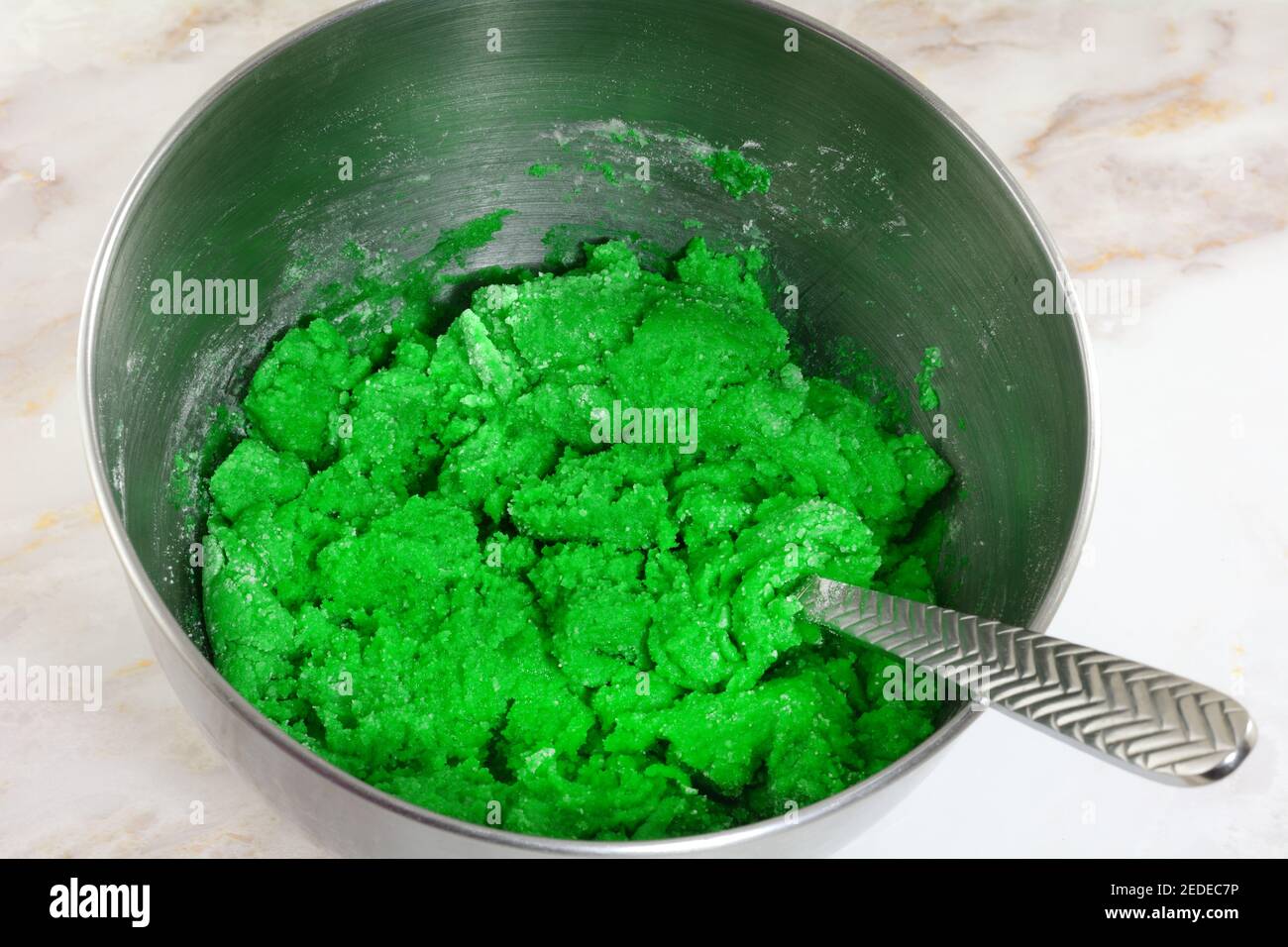 Teig für grüne St. Patrick`s Day Cookies durch Mischen Zutaten aus Mehl Butter Ei und grüne Lebensmittel Färbung Edelstahl Rührschüssel aus Stahl Stockfoto
